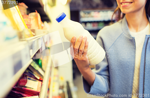 Image of happy woman holding milk bottle in market