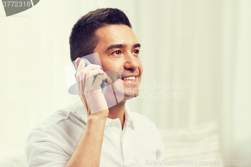 Image of happy man calling on smartphone at home