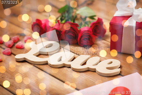 Image of close up of gift box, red roses and greeting card