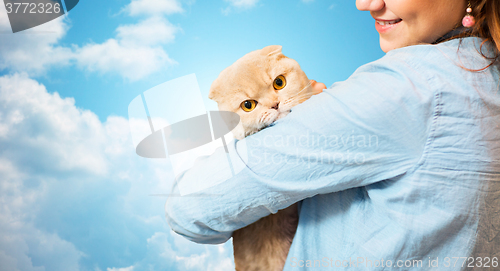 Image of happy woman holding scottish fold cat over sky