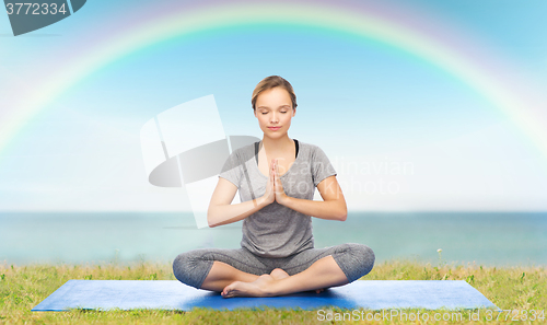 Image of woman making yoga meditation in lotus pose on mat