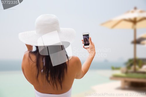 Image of woman taking selfie with smartphone on beach