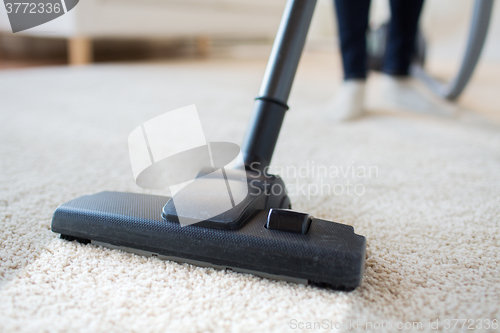 Image of close up of woman legs with vacuum cleaner at home