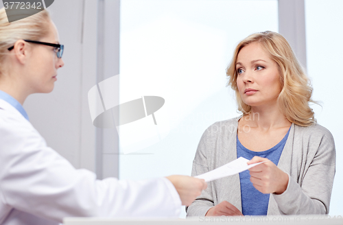 Image of doctor giving prescription to woman at hospital