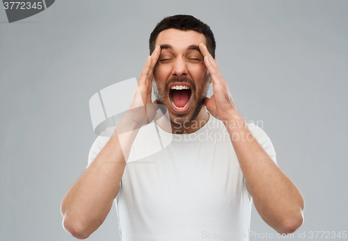 Image of crazy shouting man in t-shirt over gray background