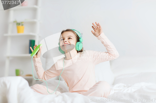 Image of girl sitting on bed with smartphone and headphones