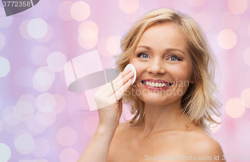 Image of happy woman cleaning face with cotton pad