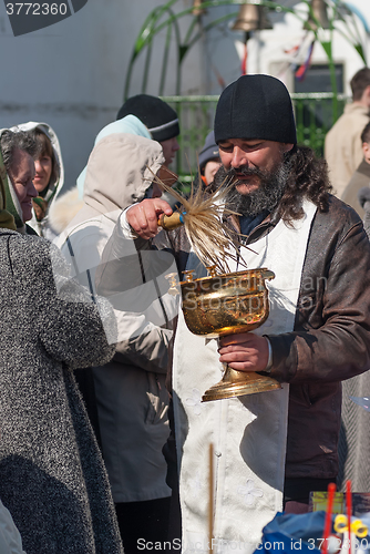 Image of Priest blessing people with holy water. Tyumen