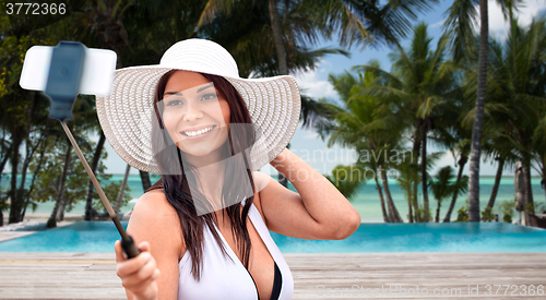 Image of smiling young woman taking selfie with smartphone