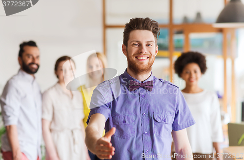 Image of happy man making handshake over office team