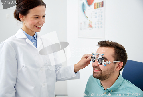 Image of optician with trial frame and patient at clinic