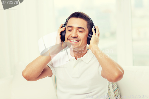 Image of happy man in headphones listening to music at home