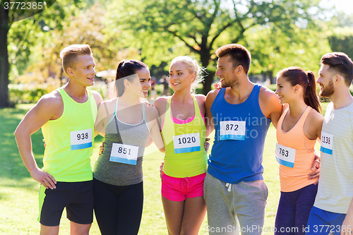 Image of happy friends or couple with racing badge numbers