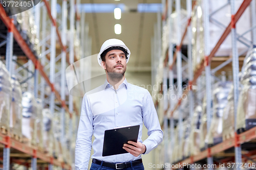 Image of happy businessman with clipboard at warehouse