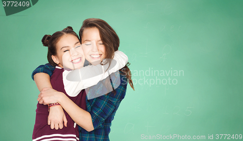 Image of happy teenage girls hugging over green board
