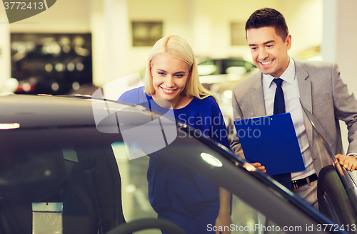 Image of happy woman with car dealer in auto show or salon