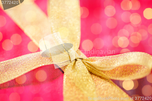 Image of close up of golden bow on red gift box