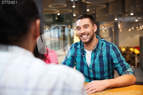 Image of happy man meeting with friends at restaurant