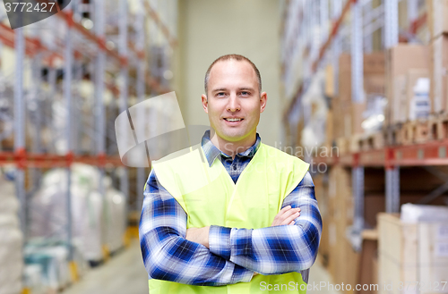 Image of happy man in reflective safety vest at warehouse