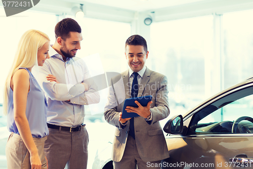 Image of happy couple with car dealer in auto show or salon