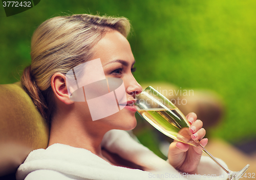 Image of beautiful young woman drinking champagne at spa