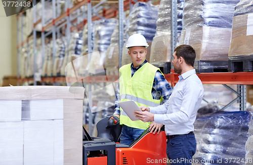 Image of men with tablet pc and forklift at warehouse