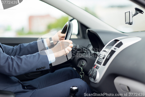 Image of close up of young man in suit driving car