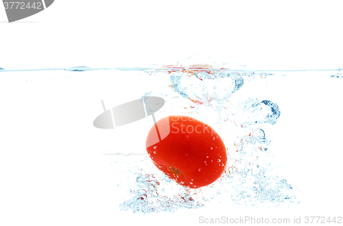 Image of tomato falling or dipping in water with splash