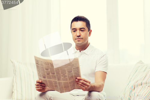 Image of man reading newspaper at home