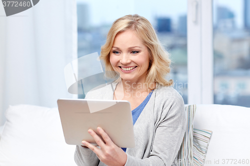 Image of happy middle aged woman with tablet pc at home