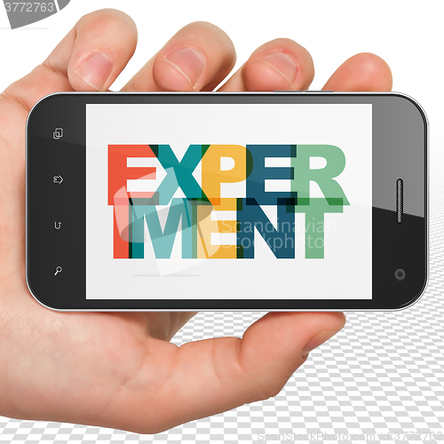 Image of Science concept: Hand Holding Smartphone with Experiment on  display