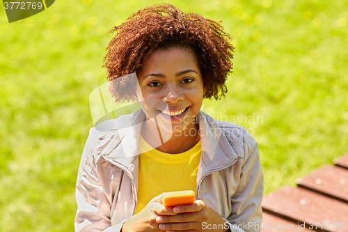 Image of happy african young woman messaging on smartphone