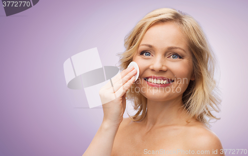 Image of happy woman cleaning face with cotton pad