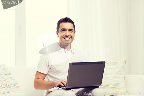 Image of happy man working with laptop computer at home