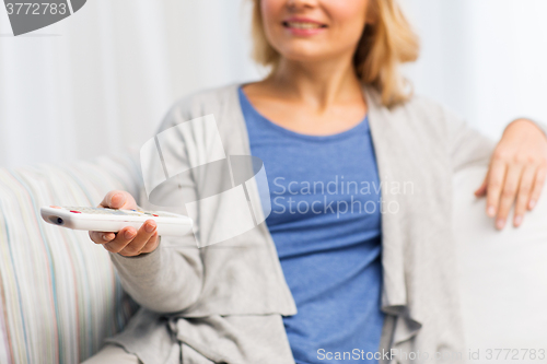 Image of close up of woman with tv remote control at home