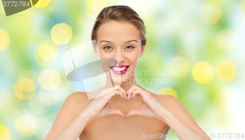 Image of smiling young woman showing heart shape hand sign