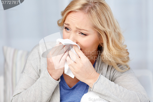 Image of ill woman blowing nose to paper napkin