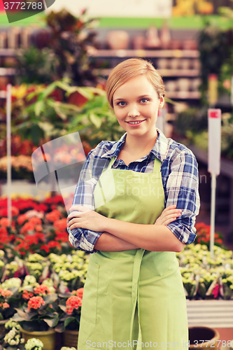 Image of happy woman with flowers in greenhouse