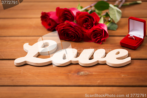 Image of close up of diamond ring, red roses and word love