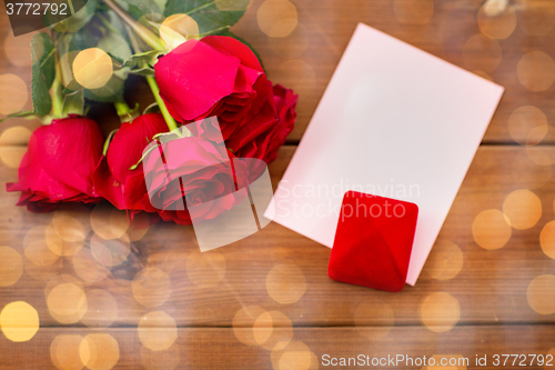 Image of close up of gift box, red roses and greeting card