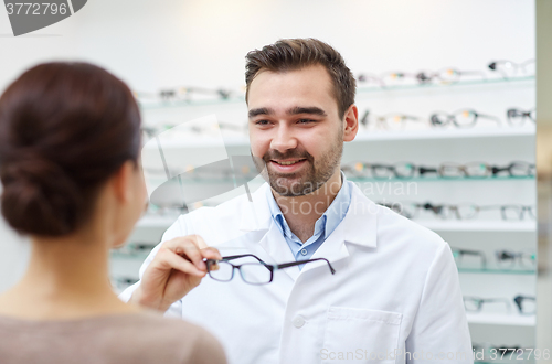 Image of optician giving glasses to woman at optics store