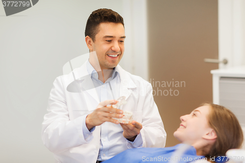 Image of happy dentist showing jaw layout to patient girl