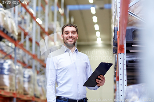 Image of happy businessman with clipboard at warehouse