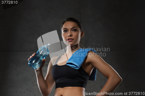 Image of woman with towel drinking water from bottle in gym