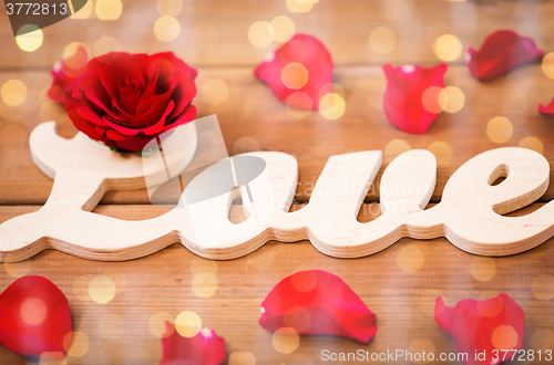 Image of close up of word love cutout with red rose on wood