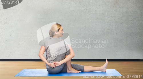 Image of woman making yoga in twist pose on mat