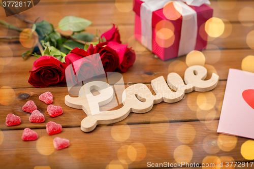 Image of close up of gift box, red roses and greeting card