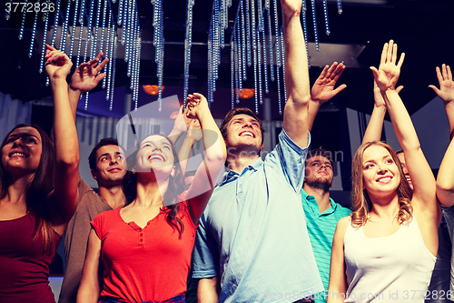 Image of group of smiling friends at concert in club