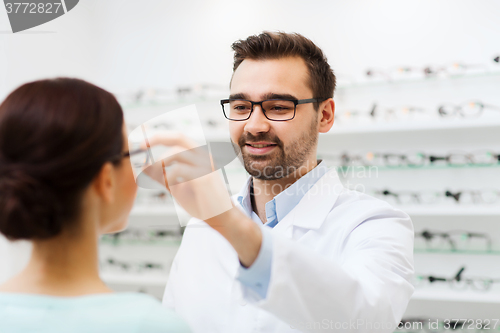 Image of optician putting glasses to woman at optics store