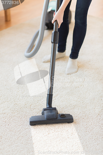 Image of close up of woman legs with vacuum cleaner at home